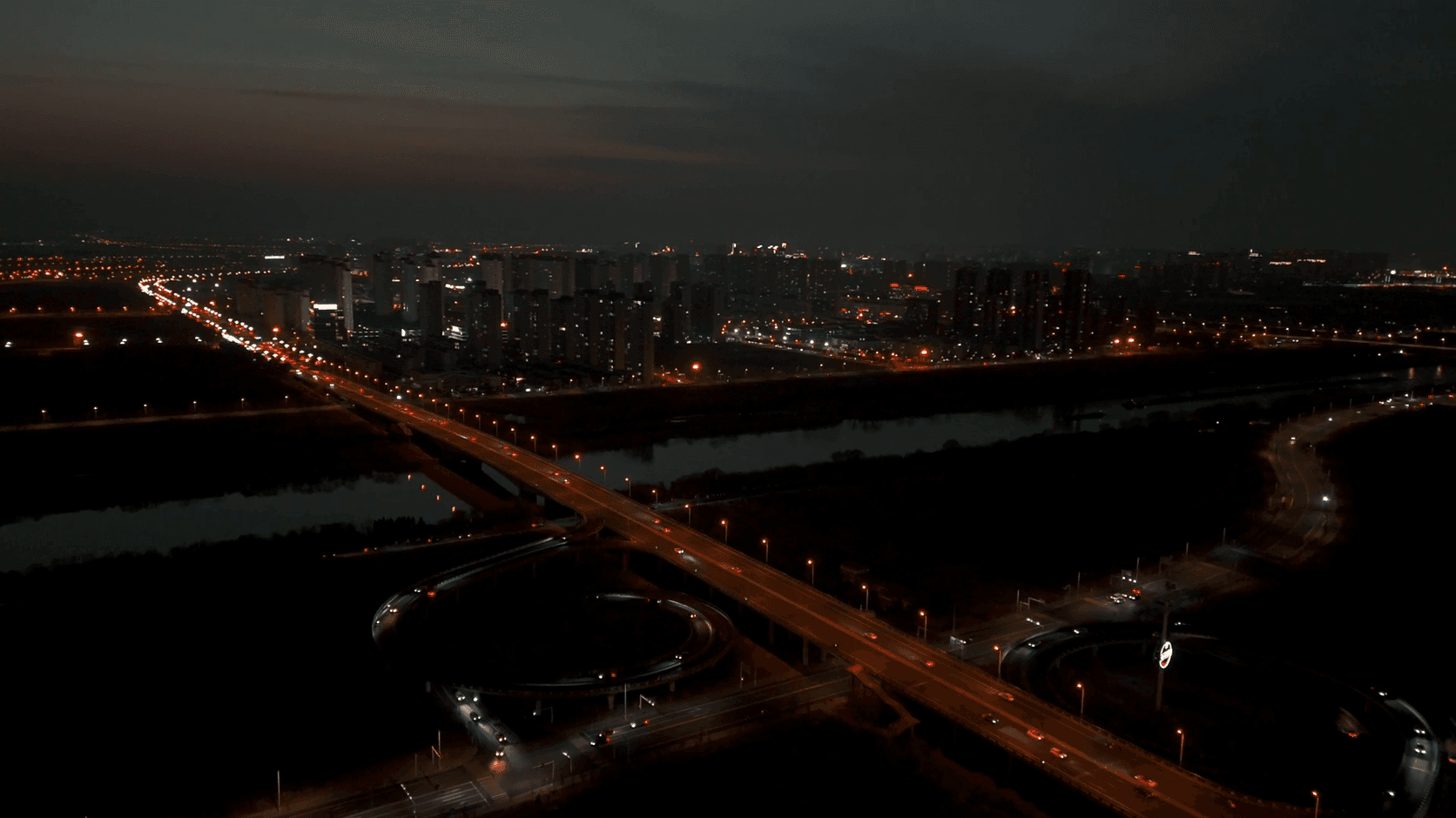 Aerial view of a city highway interchange with traffic lights at dusk